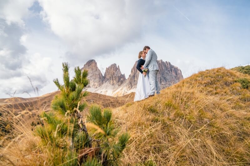 Braut und Bräutigam vor atemberaubender Bergkulisse im Allgäu. Beide stehen Kopf an Kopf sich zugewandt und genießen einen intimen Moment.